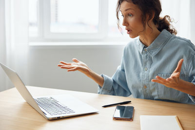 Side view of woman using digital tablet at table