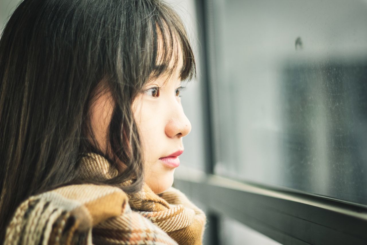 indoors, headshot, lifestyles, person, young adult, contemplation, young women, long hair, focus on foreground, leisure activity, home interior, head and shoulders, casual clothing, looking away, close-up, window, waist up, thoughtful