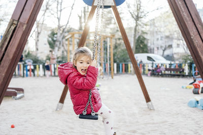 Portrait of girl sitting on swing at park