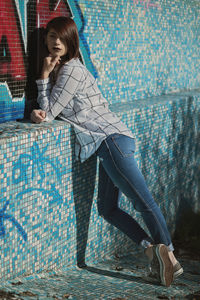 Full length portrait of young woman standing in old empty swimming pool