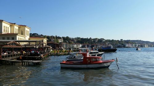 Boats in calm sea against clear sky