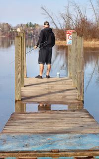 Full length of man standing on wooden post against sky