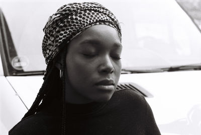 Close-up of young woman with closed eyes against car