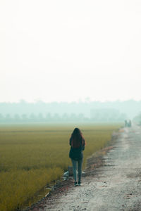 Rear view of man walking on field