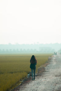 Rear view of a lady walking on field