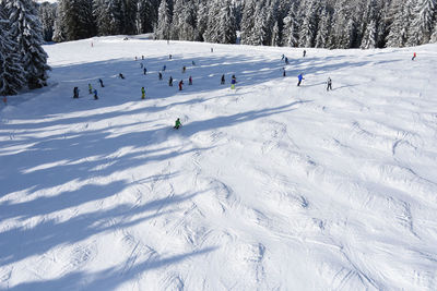 Group of people downhill skiing on snow covered field