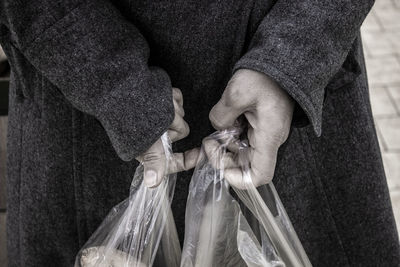 Midsection of woman holding plastic bags outdoors