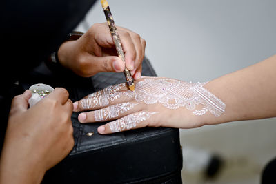 Cropped image of artist making henna tattoo on hand
