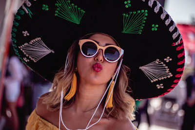 Portrait of woman wearing hat while puckering in city