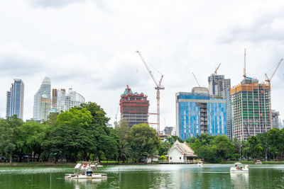 Buildings by river against sky in city