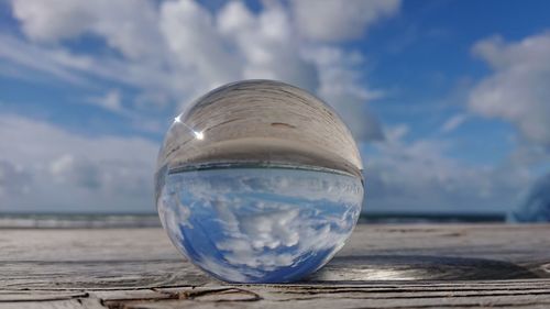 Close-up of crystal ball on glass against blue sky