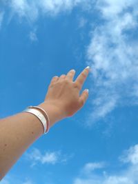 Low angle view of hand against blue sky