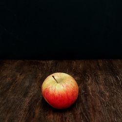 Close-up of apple on table against black background