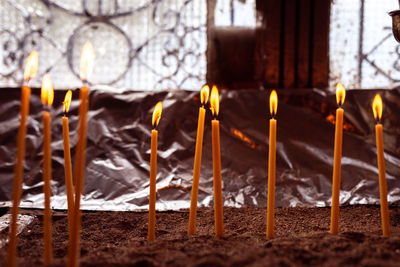 Close-up of lit candles on temple against building