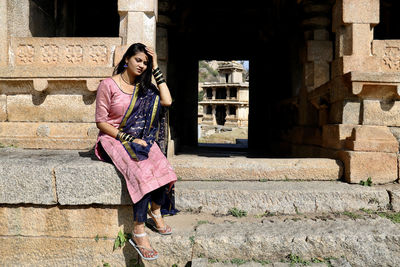 Portrait of young woman standing against wall