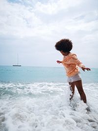 Woman standing in sea against sky