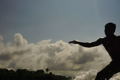 Silhouette man standing by sea against sky