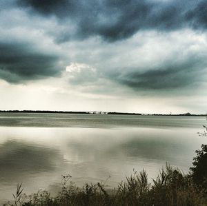 Scenic view of calm lake against cloudy sky