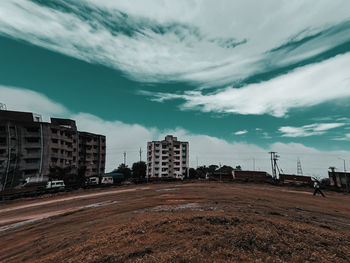 Road by buildings in city against sky