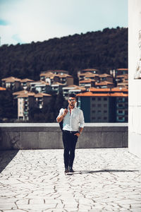 Portrait of man walking by building in city 