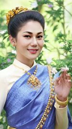 Portrait of smiling young woman standing against plants