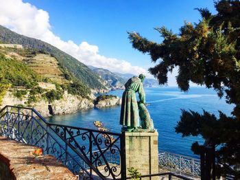 Statue by sea against blue sky