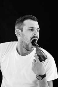 Man pointing gun in mouth against black background