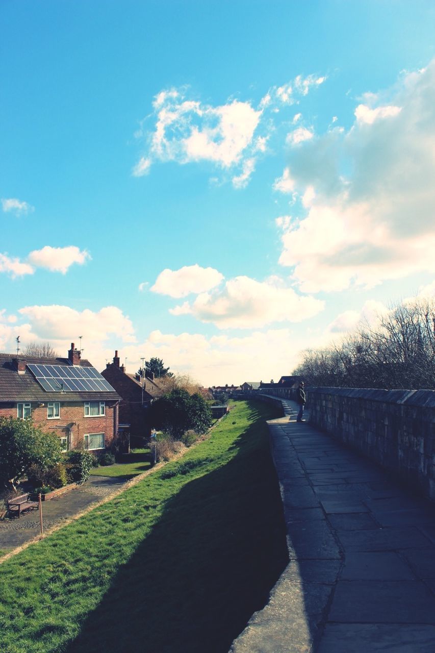 sky, the way forward, cloud - sky, tree, cloud, building exterior, built structure, road, grass, architecture, diminishing perspective, footpath, vanishing point, tranquility, walkway, tranquil scene, nature, sunlight, street, cloudy