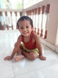 Portrait of smiling boy sitting on floor at home