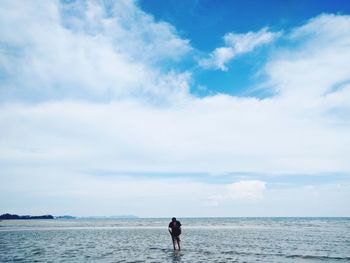 Rear view of man standing at beach against sky