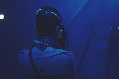 Rear view of man photographing at nightclub