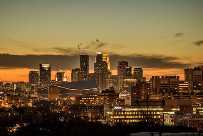 Illuminated cityscape against sky at sunset