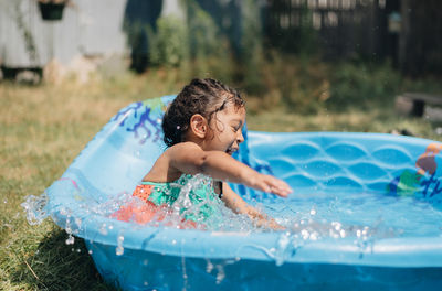 Mixed race young girl at home having fun on hot summer day in kiddie pool