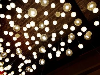 Low angle view of illuminated light bulbs hanging from ceiling