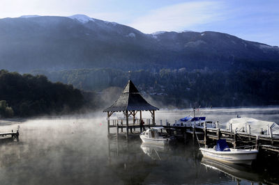 Boats moored by pier in lake against mountains