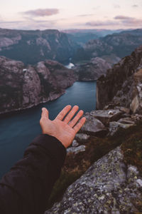 Open hand pointing to norwegian fjords view at sunset