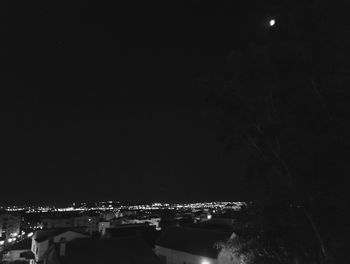 Illuminated town against sky at night