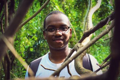 Smiling young man wearing eyeglasses at forest