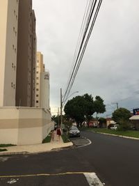 Road by buildings in city against sky