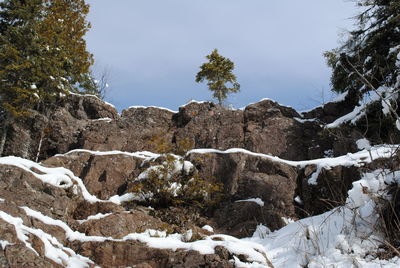 Rocks on snow covered land against sky