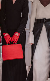 Fashion details of a knitted warm white dress, red leather gloves, handbag. fashion models posing