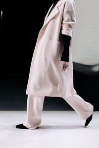 Elegant fashion details of warm long white coat, pants and black sweater, women's fashion cloth