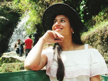 Low angle view of thoughtful young woman leaning on railing against waterfall