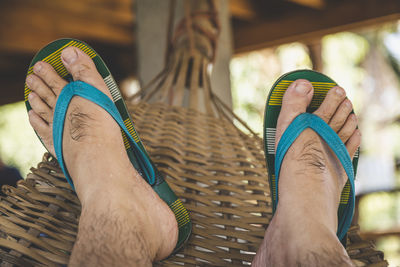 Low section of man wearing flip flop while relaxing in hammock