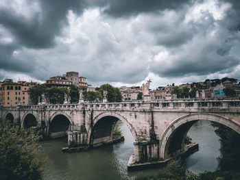 Bridge over river against cloudy sky