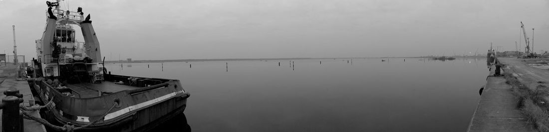 Boats moored at harbor against sky