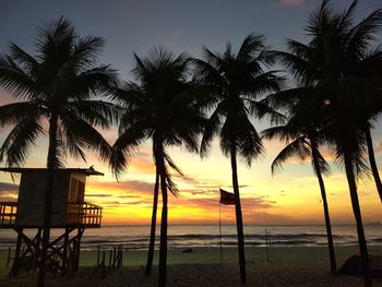 Silhouette palm trees on beach against sky during sunset