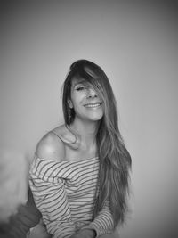 Portrait of young woman standing against wall