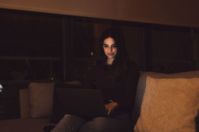 Portrait of young woman sitting on sofa at home