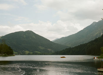 Scenic view of lake by mountains against sky